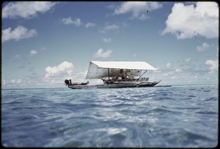 Manus: canoe with shade, Kusunan Kumayon on bow, anthropologist Geoffrey M. White under canopy, near Pere village