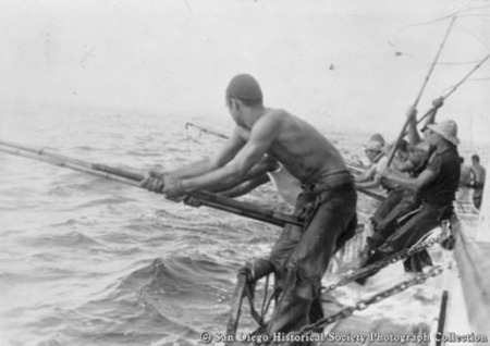 Fishermen with bamboo poles in racks on side of tuna boat Chicken of the Sea