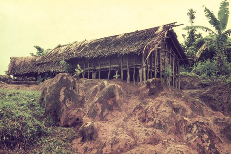Clayey subsoil, with bark-walled, palm leaf-thatched houses behind