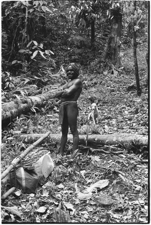 Fainjur: man and dog on trail beside cargo tied to a pole
