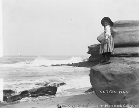 Girl standing on rock formation at La Jolla beach