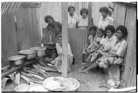 Christian women in a kitchen with walls of iron roofing.