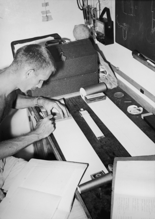 Arthur E. Maxwell works on heat probe records during the Capricorn Expedition