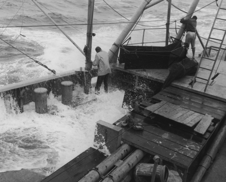 Two men working aboard R/V Horizon during storm, MidPac Expedition