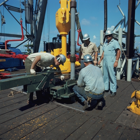 Roughnecks doing some rig floor operations during the Deep Sea Drilling Project operation aboard the D/V Glomar Challenger...