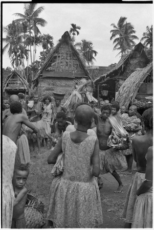 Mortuary ceremony: woman holds banana leaf bundles (wealth items) aloft during exchange