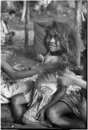 Young girl with long hair, other children smoothing her hair