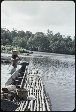 Canoes: woman loads baskets of yams onto canoe used for coastal transport