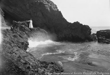 Woman in white dress standing on rock on La Jolla coast