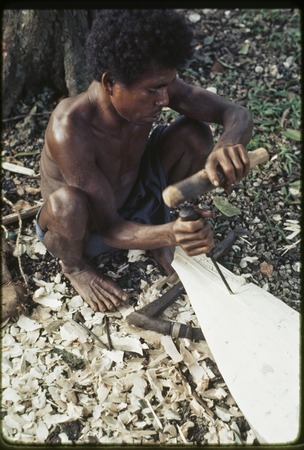 Canoe-building: man carves nipawa (grasshopper) design on prow
