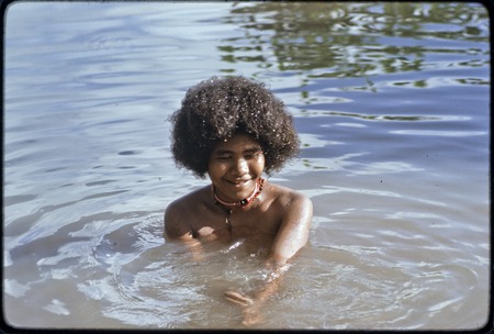 Young woman, wearing shell necklaces, bathes in shallow water