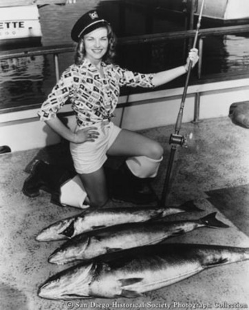 Queen of 16th Annual San Diego Yellowtail Derby Sharon Wetzell posing with fishing rod and yellowtail tuna