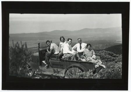 Unidentified people in open-top truck, with landscape view in background