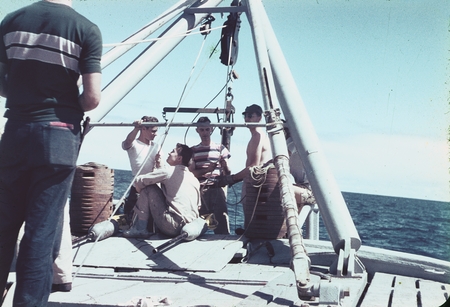 Jeffery D. Frautschy (center in stripped T-shirt) with other unidentified men near the A-frame on the fantail of R/V Horiz...