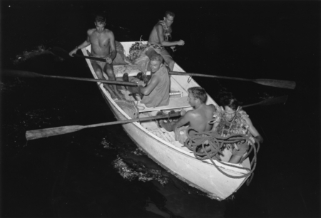 Men use a skiff at night during the Capricorn Expedition