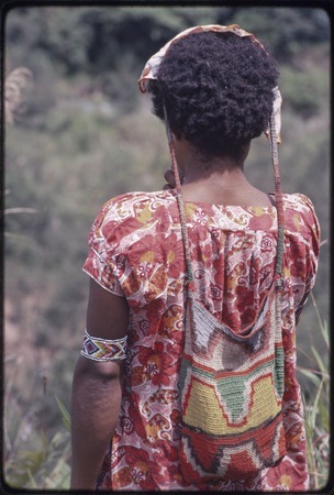 Western Highlands: woman wearing colorful net bag (bilum) suspended from head, beaded armband