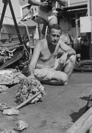 Roger Revelle sits on the deck of R/V Spencer F. Baird and examines a sample from Alexa Bank, Samoa