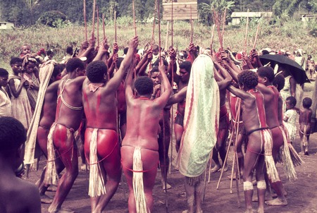 Women and girls with red body paint perform a circle dance