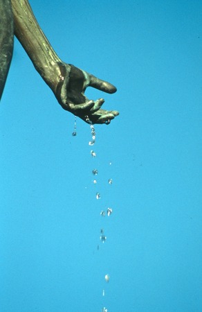 Standing: detail view of bronze figure&#39;s left hand dripping water