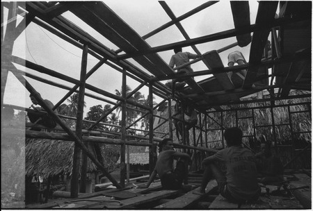 House-building: men construct roof and frame
