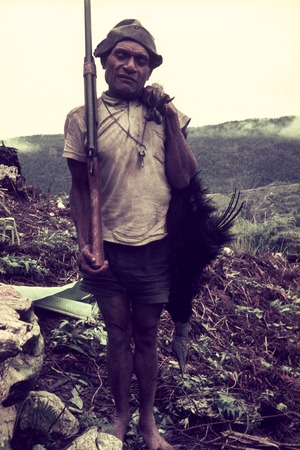 Hunter with his shotgun and a cassowary he has killed