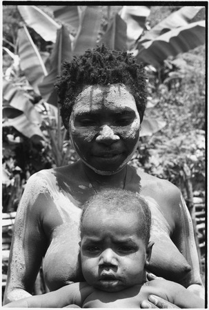 Bomagai: woman, wearing clay as sign of mourning, holds infant