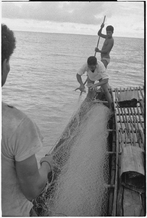 Fishing: man removes fish from net on board a canoe