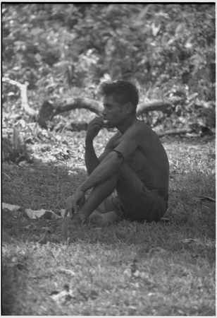 Young man sits on grass, eating