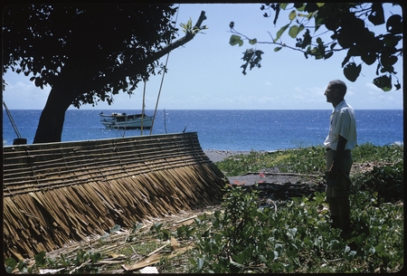 Man standing by thatch canoe covering, Makira.