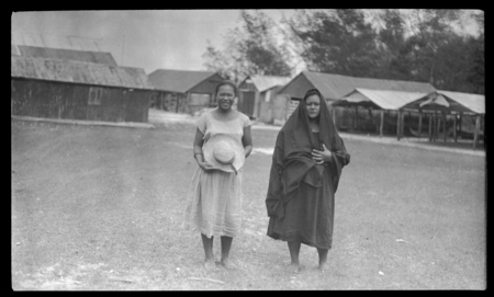 Two Cook Islands women, buildings in background
