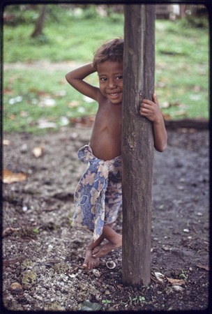 Young boy leans on a post and smiles