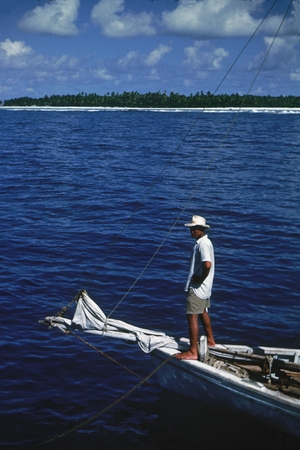 Standing on the bow of a boat is a Samoan native, as photographed by a member of the Capricorn Expedition (1952-1953) duri...