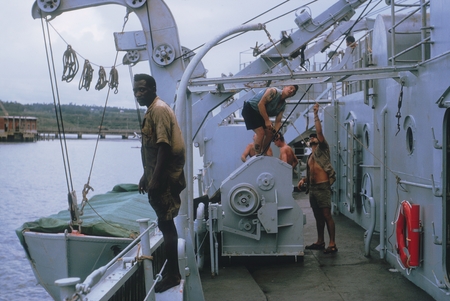 Aboard the Argo on the Lusiad Expedition: local native onboard while crew works on davits. March 1963