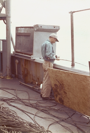 Scientist Sydney Charles Rittenberg is fishing off the side of the R/V Horizon during the MidPac expedition. 1950.