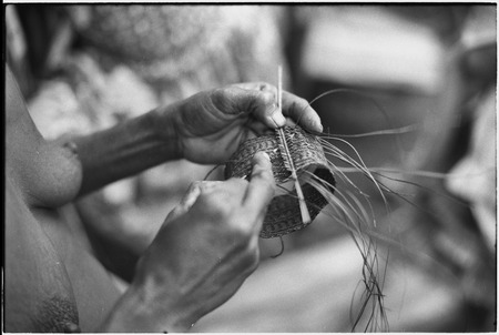 Weaving: woman plaits an armband, Omarakana