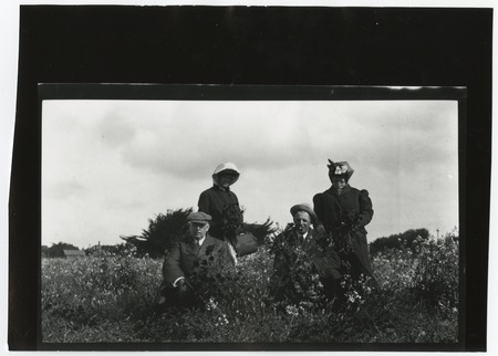 Ed Fletcher with unidentified people, posing outdoors in a field