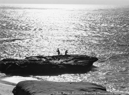 Distant view of men fishing from rock on La Jolla coast