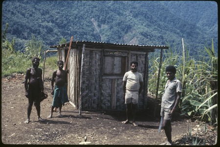 Wando, Kimi and other men outside of small tin-roofed tradestore