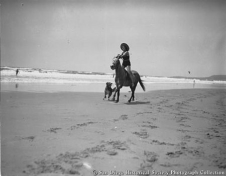 Woman horseback riding on beach
