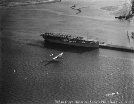 China Clipper flying low next to aircraft carrier on San Diego Bay