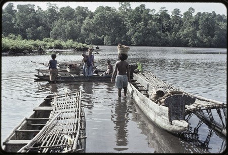 Canoes: women load baskets of yams and other items onto canoe used for coastal transport