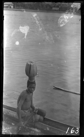 Young man in canoe wearing initiation cap, Bougainville