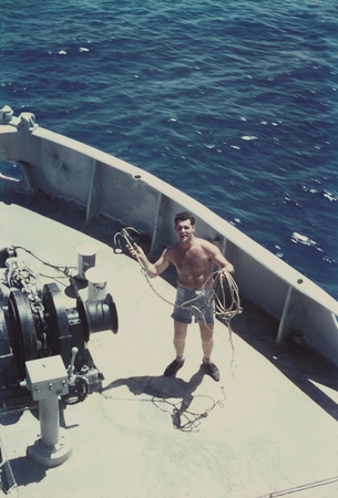 An unidentified member of the crew of the MidPac Expedition (1950) holding a small anchor on the research vessel Horizon. ...