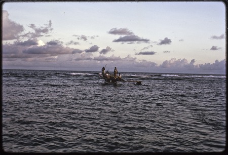 Manus: canoe approaches the beach at Pere, waves break on coral reef in background,