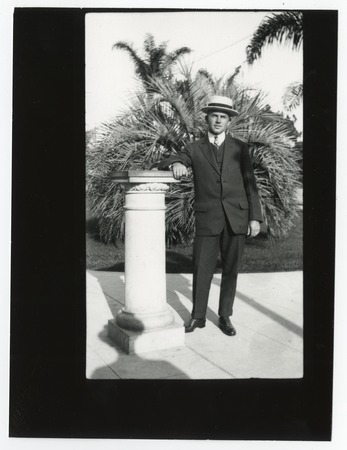 Unidentified young man in suit, posing near column