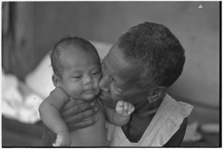 Elderly woman, Bomtavau, kisses young infant