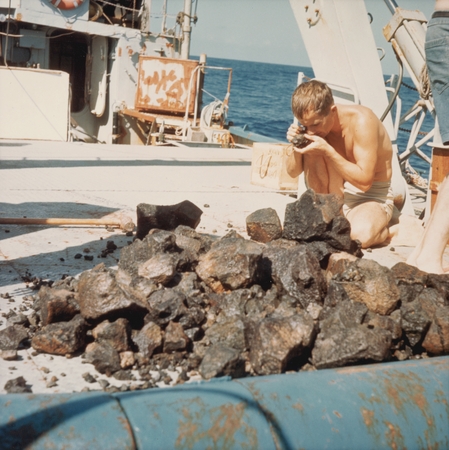 Man examining contents of dredge haul with loop