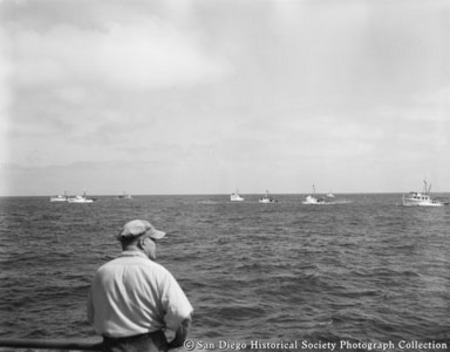 View of tuna fleet from deck of boat with man in left foreground