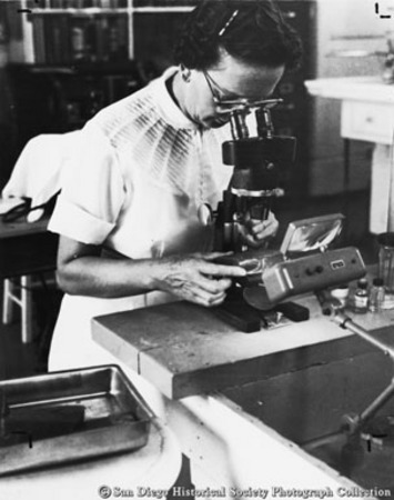 Thelma Selby looking through microscope at American Agar Company laboratory