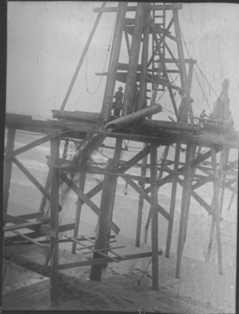 This photo depicts construction workers emptying the sand bucket during construction of the original pier at the Scripps I...